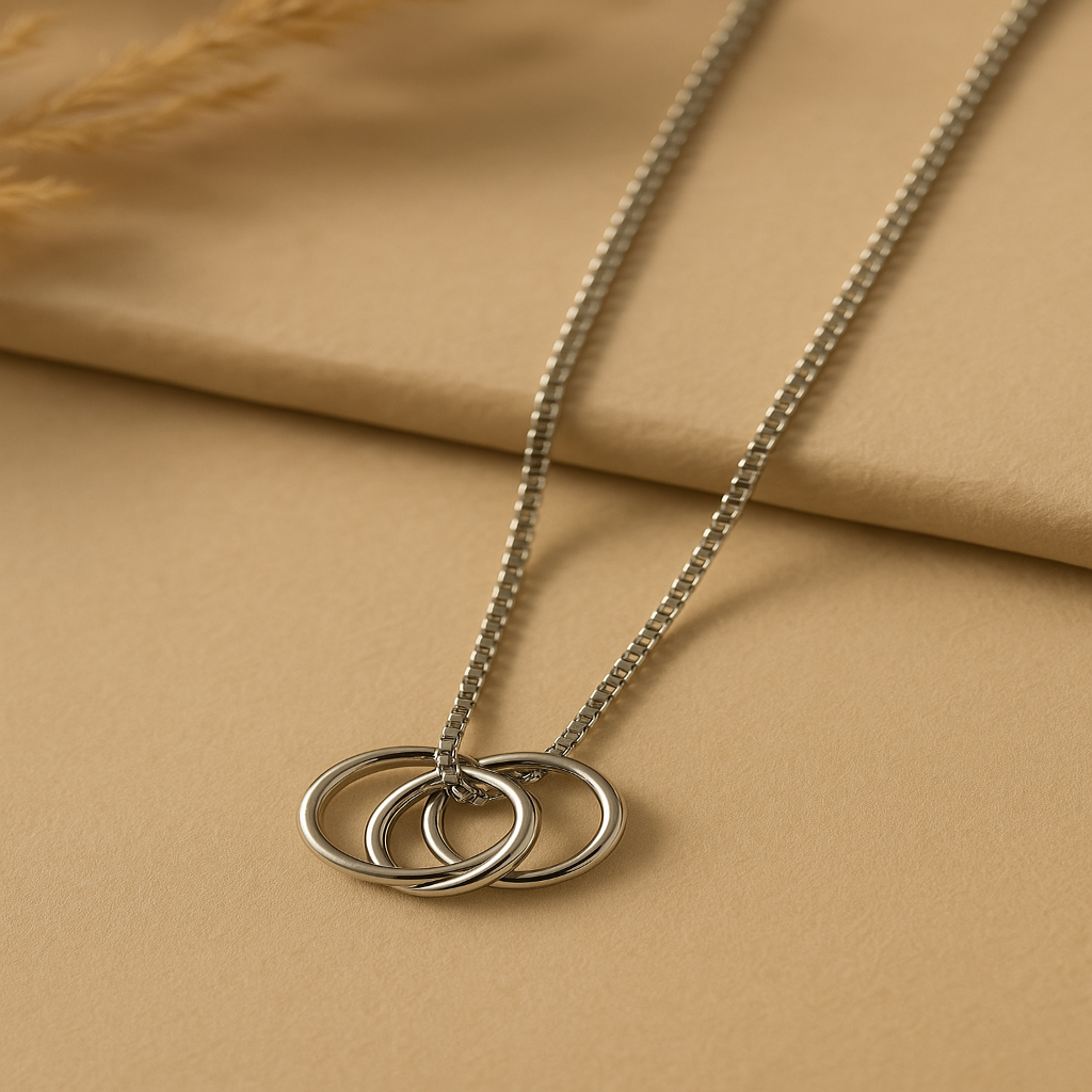 Silver necklace with three interlocking rings on a beige fabric background