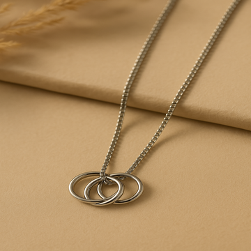 Silver necklace with three interlocking rings on a beige fabric background