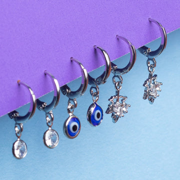 Silver nose rings with various charms on a blue and purple gradient background
