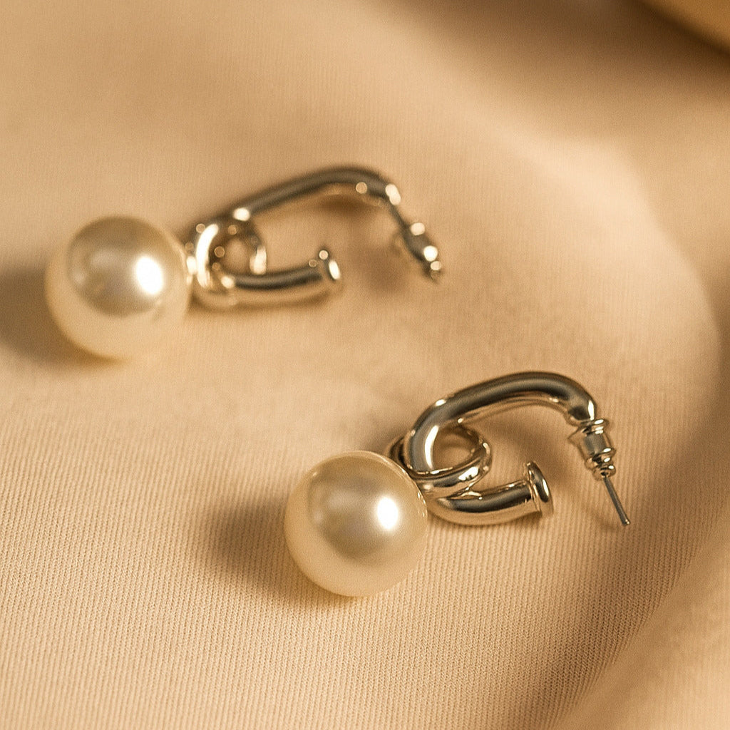 Gold hoop earrings with pearls on a beige fabric background
