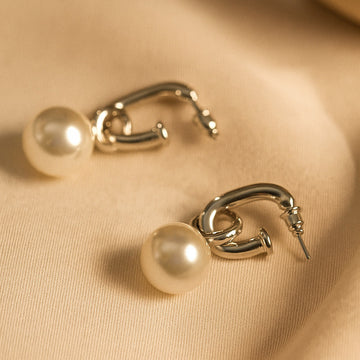 Gold hoop earrings with pearls on a beige fabric background