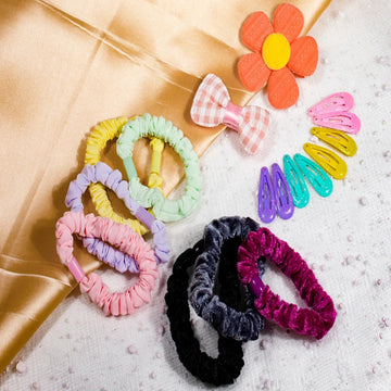 A collection of acolorful soft silky satin scrunchies displayed on  surface, with a variety of colors and patterns including plain solid colors and printed designs.