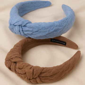 Two knotted headbands, one blue and one brown, on a beige background.