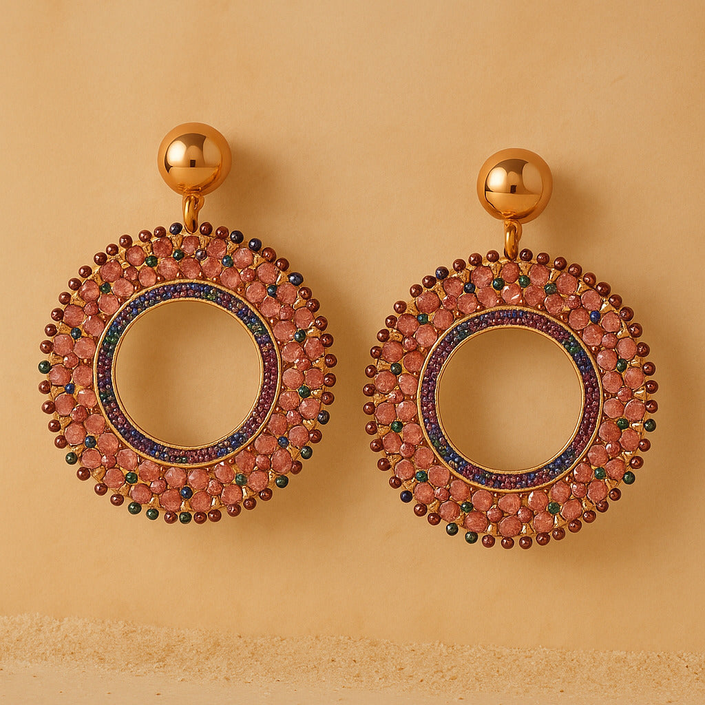 Gold earrings with circular design and gemstones on a beige background