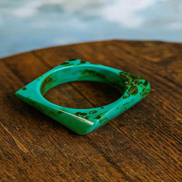 Green ceramic ring on a wooden surface with a blurred natural background