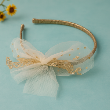 Gold headband with a white bow on a light blue background