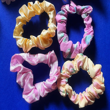 A collection of stretchable hair bands in various colors including pink, yellow, and multicolored patterns, displayed on a blue background
