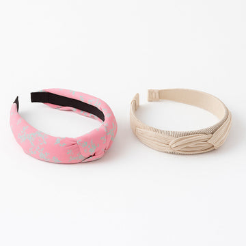 Two headbands, one pink with black pattern and one beige, on a white background