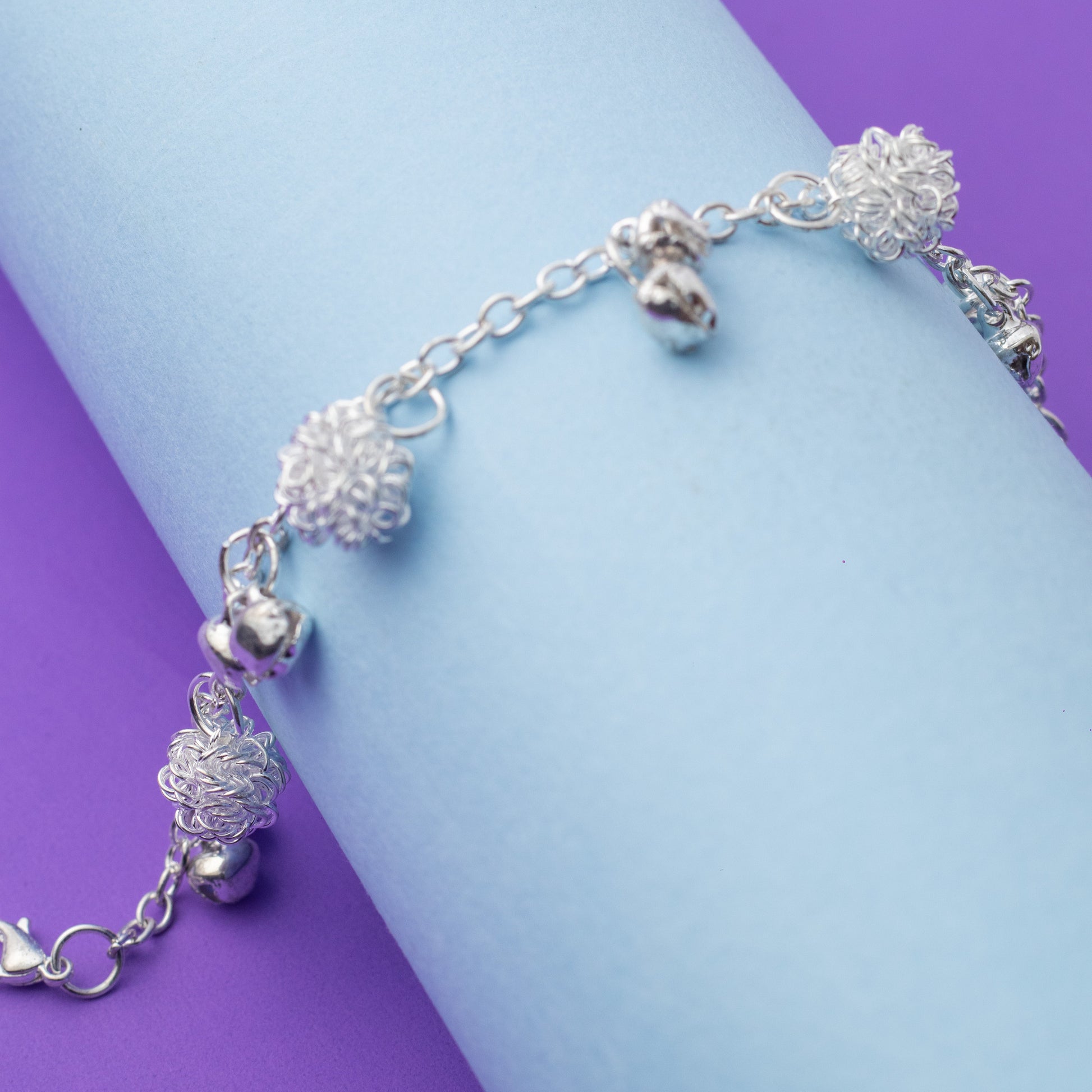 Silver bracelet with decorative beads on a purple and blue background