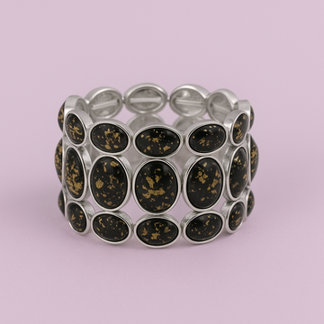 Silver bracelet with black circular stones on a light purple background