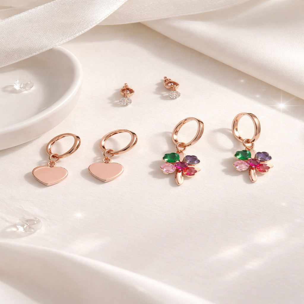 Set of earrings including heart-shaped and clover designs on a white surface.
