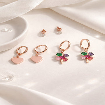 Set of earrings including heart-shaped and clover designs on a white surface.