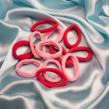 A collection of red and pink rubber bands arranged on a blue silky surface.