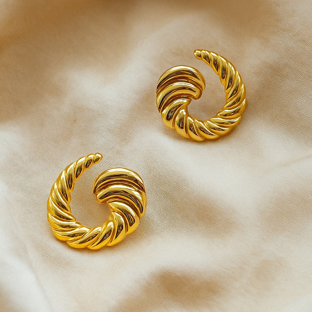 Pair of gold hoop earrings on a beige fabric background