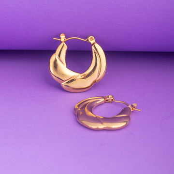 Gold hoop earrings on a purple background