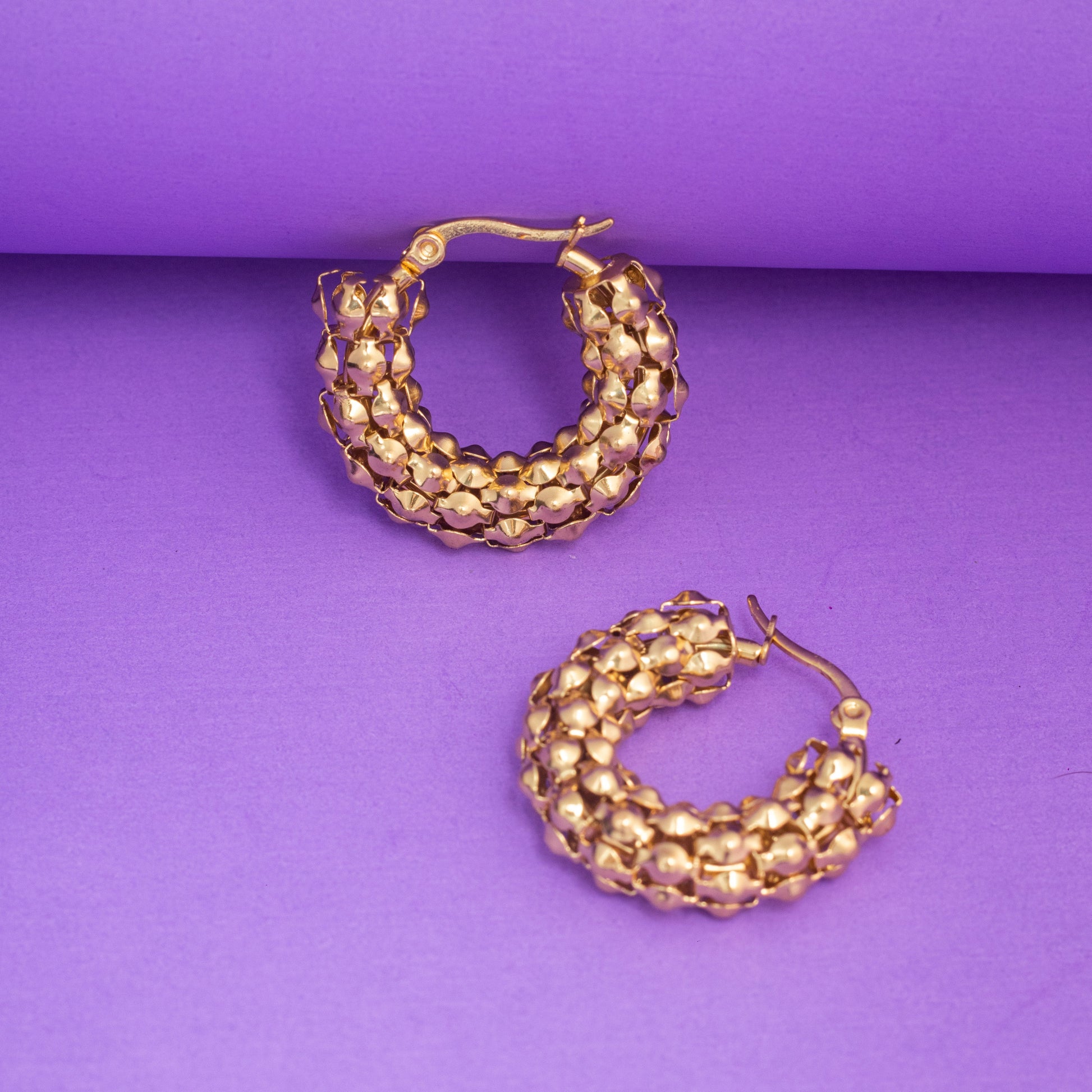 Gold hoop earrings on a purple background