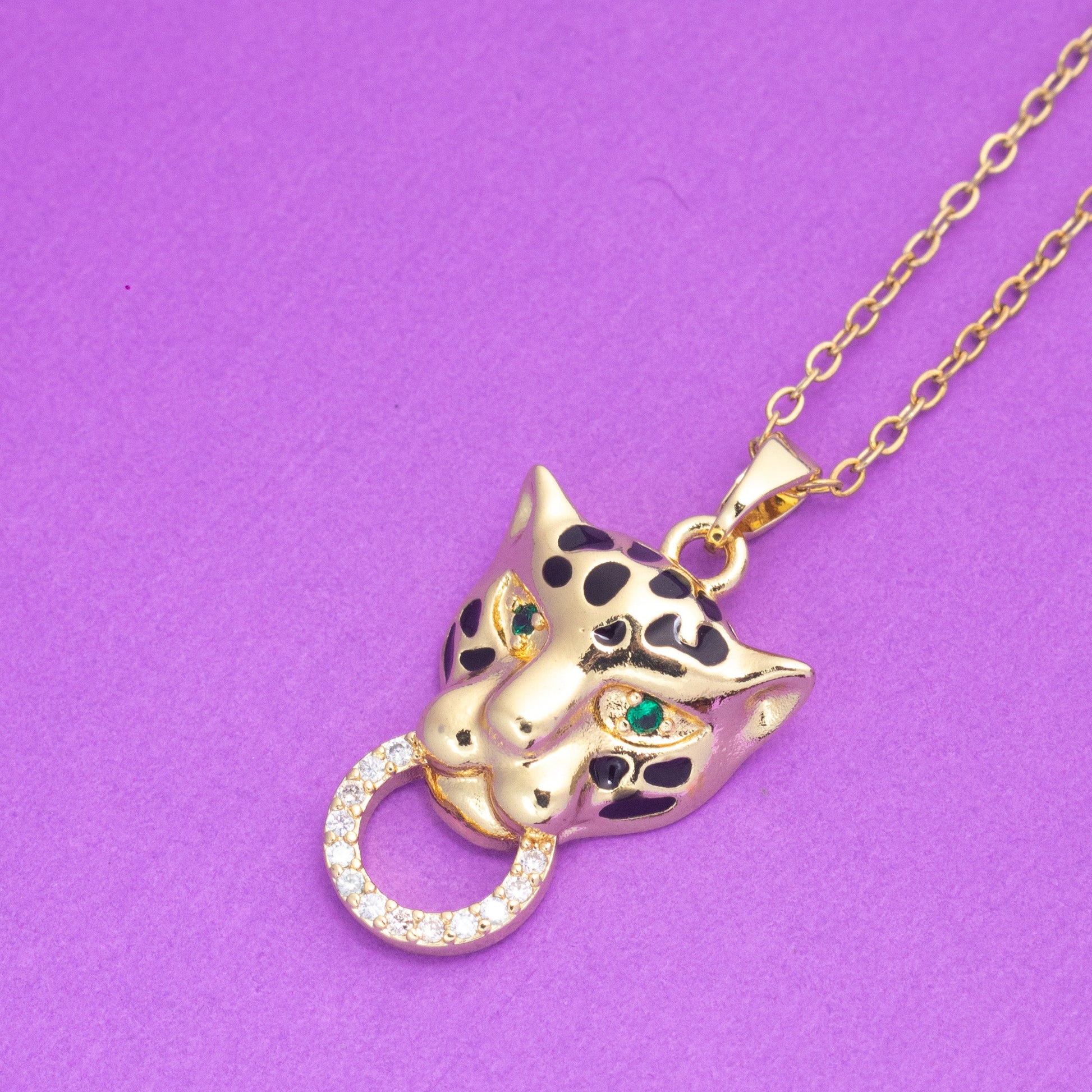 Gold panther necklace with gemstones on a purple background