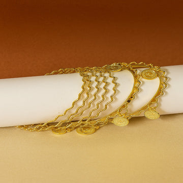 Gold bracelet with coin details on a white cylindrical object against a brown background