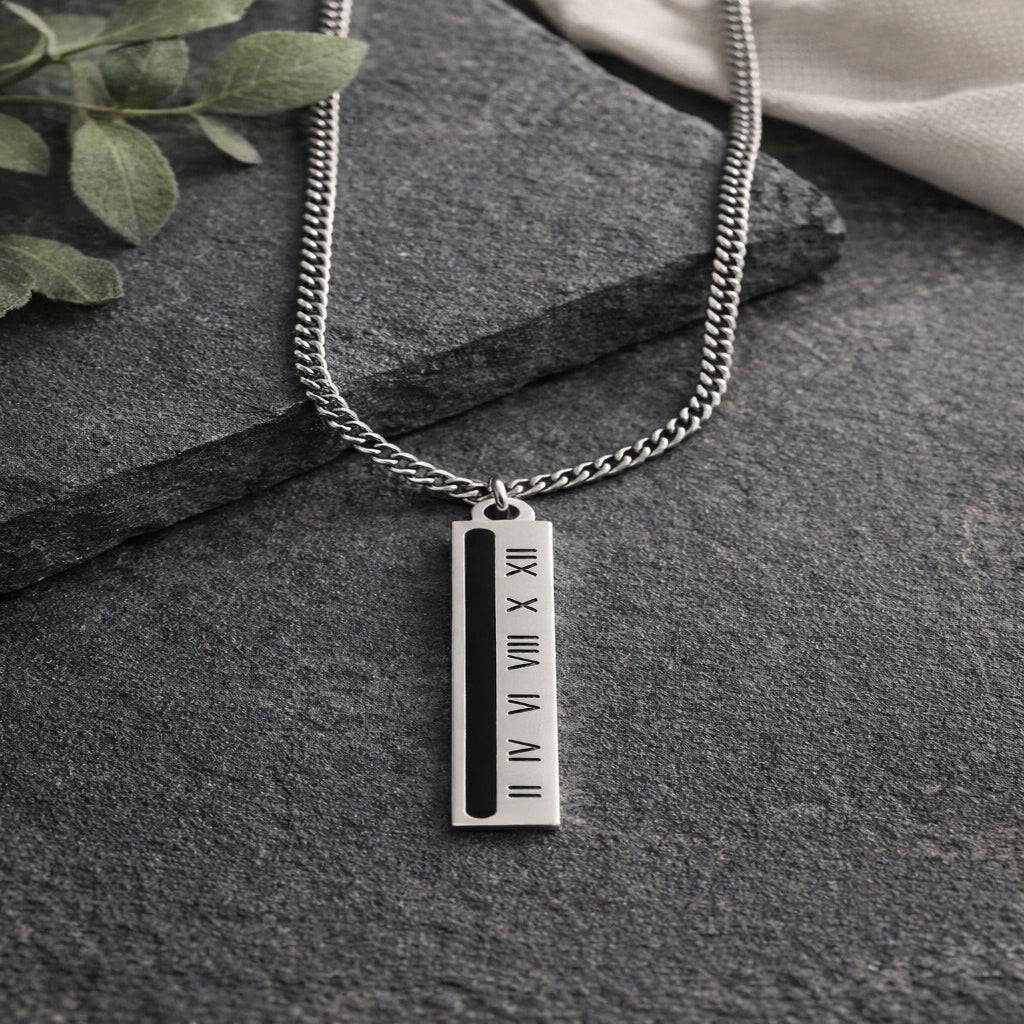 Silver mens  necklace with a vertical tag on a dark stone surface